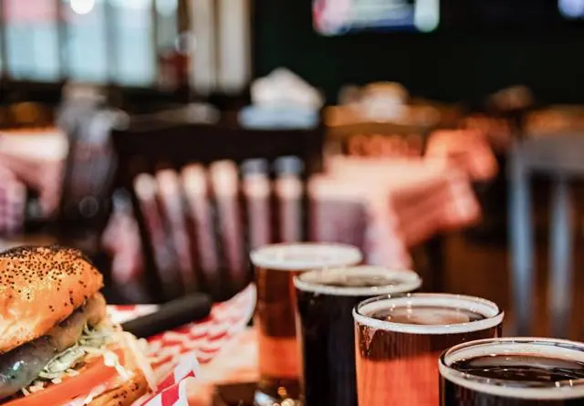 A lineup of various beers in glasses on a bar counter.